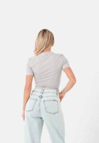 Grijze t-shirt met korte mouwen, strakker bij de taille, gecombineerd met lichtblauwe hoge taille denim jeans met achterzakken, eenvoudig ontwerp en een gladde textuur.