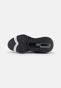 Musta-valkoinen urheilukengän pohja, jossa on ruutukuvio ja aaltoileva kuvio, pyöreä Nike-logo ja "superrep"-teksti pohjassa.