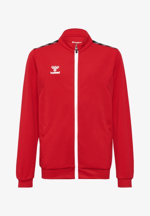 Rote Trainingsjacke mit strukturiertem Finish, weißem Reißverschluss, Seitentaschen und schwarzem Chevron-Muster entlang der Schultern. Hummel-Logo in Weiß.