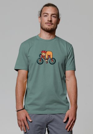 Grünes Baumwoll-T-Shirt mit einem bunten Cartoon-Design eines Radfahrers in kräftigem Orange und Rot auf einem Fahrrad mit schwarzen Rädern. Kurze Ärmel, Rundhalsausschnitt.