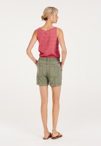 Rode mouwloze tanktop gecombineerd met olijfgroene shorts met een elastische tailleband en twee achterzakken. Soepele stof en casual ontwerp.