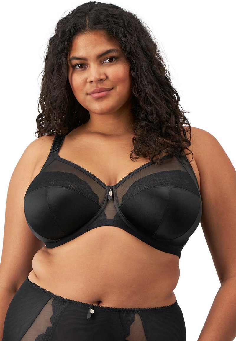 Soutien-gorge noir avec armatures, panneaux en maille et détails en dentelle. Bretelles réglables et embellissement décoratif au centre devant.