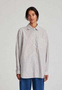 Striped long-sleeve shirt in light gray and white, featuring a button-up design, collar, and a single chest pocket. Soft fabric texture.