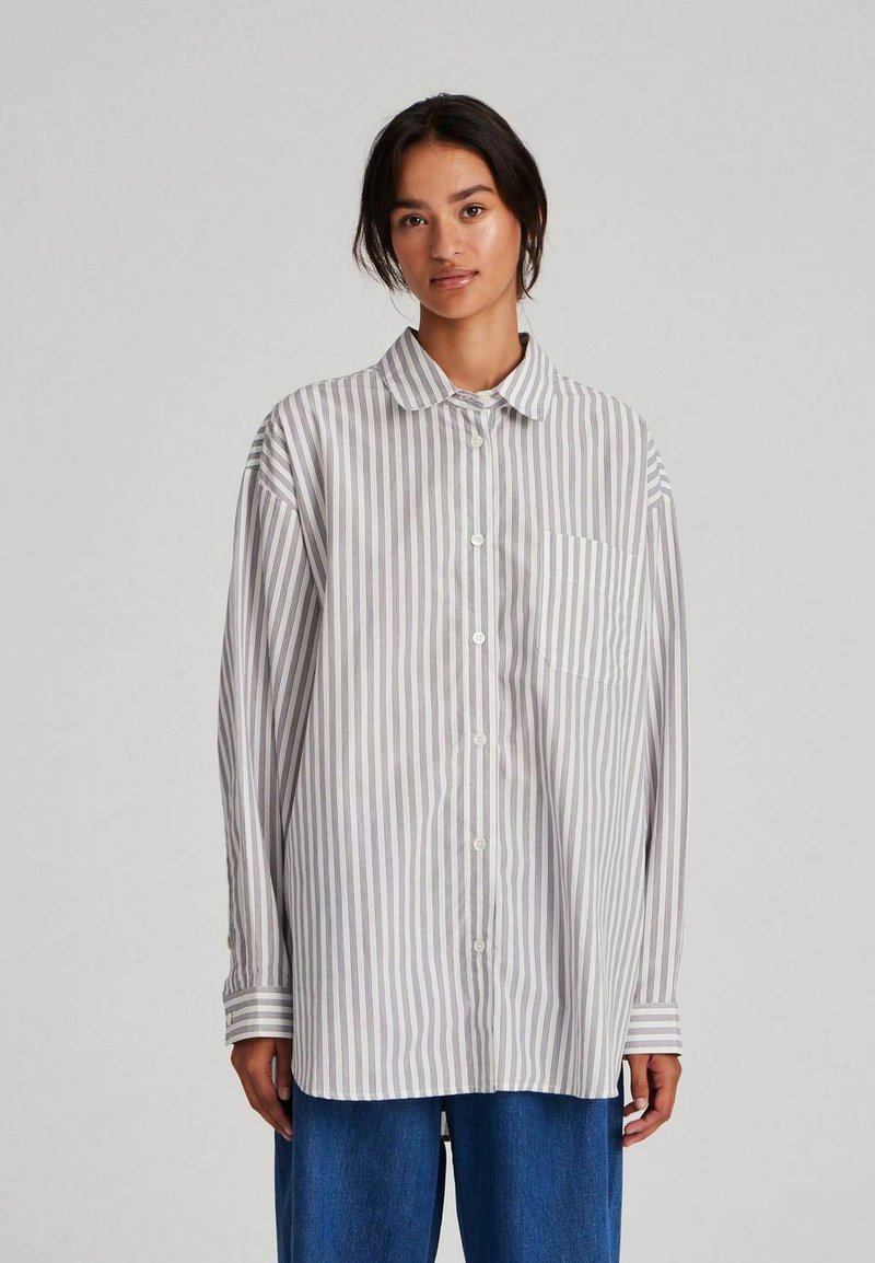Striped long-sleeve shirt in light gray and white, featuring a button-up design, collar, and a single chest pocket. Soft fabric texture.