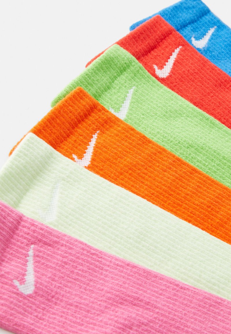 Calcetines coloridos en rosa, verde, naranja, rojo y azul, presentando una textura de canalé y el logo blanco de Nike en cada uno.