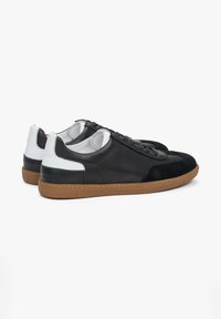 Zwart-witte leren sneakers met trendy suede accenten, ronde neus, platte rubberen gumzool en geperforeerde details aan de zijkanten.