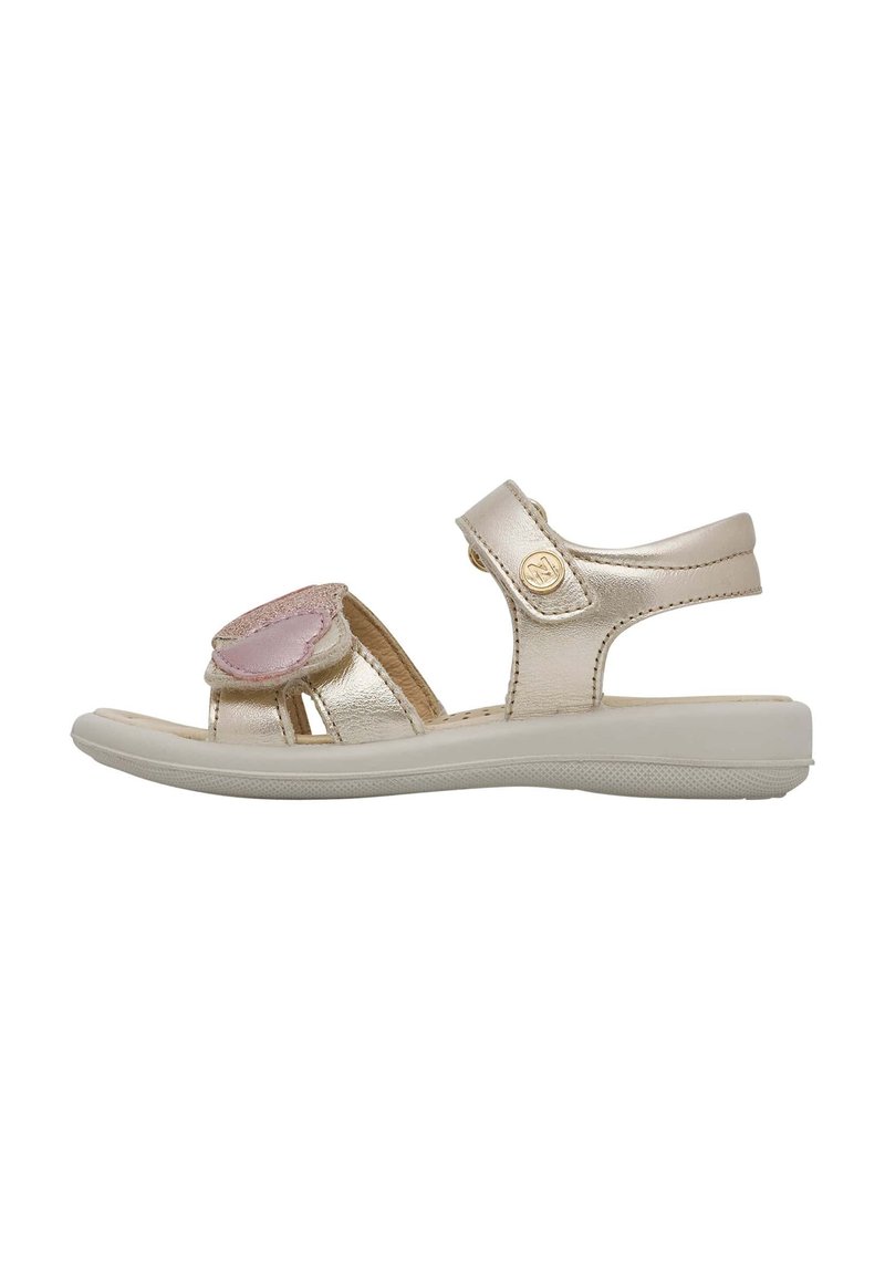 Sandali metallici oro con punta aperta, fascia regolabile e decorazione in pelle rosa, dotati di suola piatta bianca e parte superiore testurizzata.