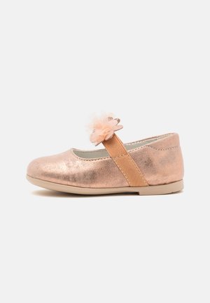 Baleriny w kolorze różowego złota z metalicznym wykończeniem, elastycznym paskiem i akcentem z tiulowego kwiatu. Gładka faktura i zaokrąglony kształt noska.