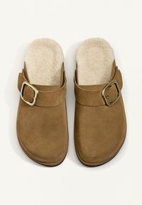 Hnedé semišové nazúvacie dreváky s nastaviteľnými mosadznými prackami a krémovo sfarbeným mäkkým fleecovým podšívkou.