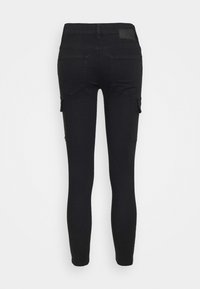 Jean noir à coupe ajustée, avec deux poches arrière et une poche cargo latérale. Le matériau est du denim avec des détails de couture minimalistes.
