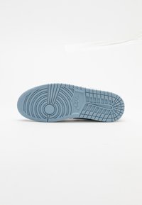 Semelle de basket Nike bleu clair avec motifs circulaires et en grille sur fond blanc.