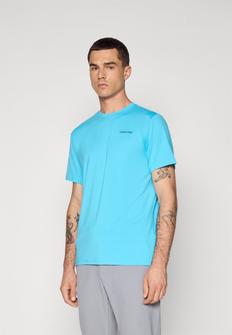 Hellblaues T-Shirt mit kurzen Ärmeln aus glattem Stoff, mit Rundhalsausschnitt und kleinem schwarzen "Calvin Klein"-Logo auf der Brust.