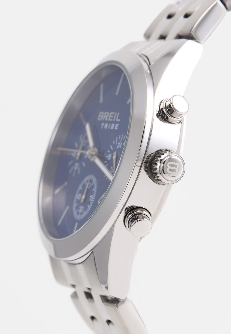 Reloj de acero inoxidable plateado con esfera azul, características de cronógrafo, tres subesferas y una correa texturizada con acentos recortados.