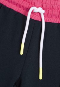 Marina blå sweatshirtbyxor med en rosa elastisk midja och en vit dragsko, med gula spetsar på dragskon för extra detalj.