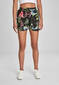 Černé květinové šortky s živými růžovými, modrými a zelenými vzory, s elastickým pasem a volným střihem. V kombinaci s bílými teniskami.