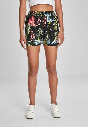 Sorte blomstrede shorts med livlige pink, blå og grønne mønstre, med elastisk talje og løs pasform. Sammen med hvide sneakers.