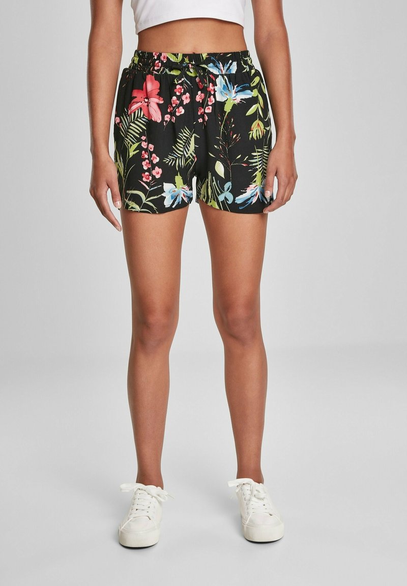 Černé květinové šortky s živými růžovými, modrými a zelenými vzory, s elastickým pasem a volným střihem. V kombinaci s bílými teniskami.
