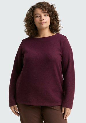 Pull en bordeaux à manches longues, col rond, en tissu texturé, coupe décontractée, associé à un pantalon marron. Design simple, sans motifs visibles.
