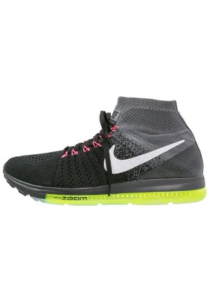 Scarpa da corsa Nike alta nera e grigia con lacci rosa, logo swoosh bianco e suola Zoom Air giallo neon, vista laterale su sfondo bianco.