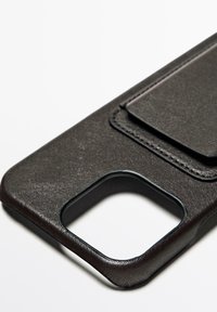 Housse de téléphone en cuir noir avec une finition texturée, comportant une ouverture pour l'accès à la caméra et une poche à rabat à l'arrière pour des cartes.