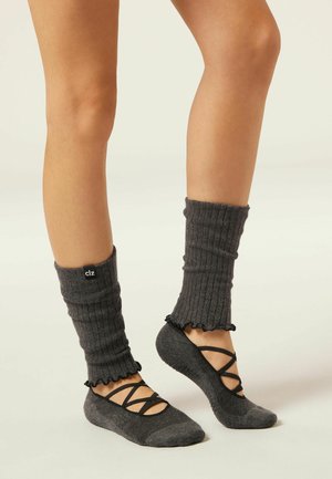 Jambières grises à côtes avec des bords volants, assorties à des chaussettes grises avec des lanières croisées et des semelles texturées.