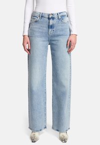 Jeans a gamba larga di colore blu chiaro, realizzati in denim, con vita alta, due tasche frontali e dettagli a orlo grezzo. Abbinati a scarpe con tacco a fantasia.