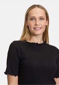 Czarny prążkowany t-shirt z krótkimi rękawami, z falbany na mankietach i dekolcie, wykonany z gładkiego, elastycznego materiału.