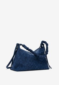 Navy blue leather handbag with a triangular shape, ruched handle, embossed floral design, and a zip closure. Features a detachable shoulder strap.