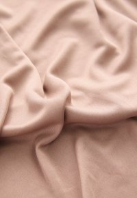 Hellrosa, dehnbare Stoffbahn, die in sanften Falten drapiert ist und eine glatte Textur mit einem feinen Rippenmuster für zusätzliche Details zeigt.