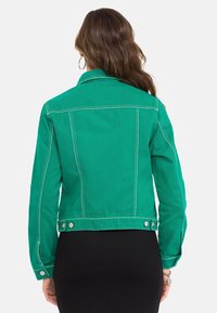 Grüne Jeansjacke mit einem verkürzten Design, kontrastierenden weißen Nähten, Knopfverschluss an der Taille und seitlichen Taschen.