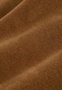Tissu brun texturé avec une finition douce et pelucheuse ainsi qu'un motif en relief subtil. Le matériau semble épais et chaud, adapté pour les vêtements ou le rembourrage.