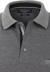 Graues Polohemd aus einem strukturierten Stoff, mit kontrastierendem Kragen, einer Knopfleiste mit drei Knöpfen und einer kleinen Brusttasche. Das Etikett lautet "CASA MODA, Easy Care."