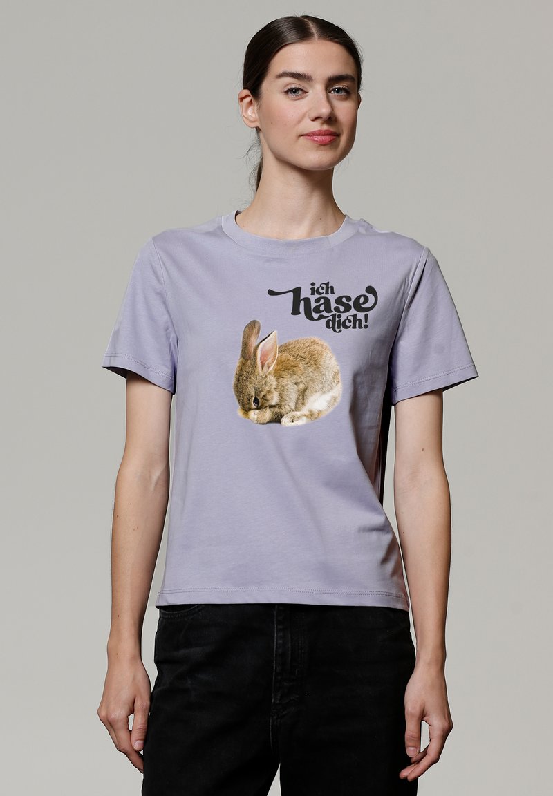 Lavendelfarbenes Baumwoll-T-Shirt mit einem Grafikdesign eines schlafenden Kaninchens und dem Text "ich hasse dich!" in Schwarz, mit kurzen Ärmeln und rundem Ausschnitt.