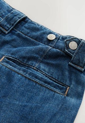 Jeans aus Denim in einem dunkelblauen Farbton, ausgestattet mit zwei silbernen Knöpfen, einer Vordertasche und sichtbaren Nähdetails. Die Textur ist glatt mit einem leichten Glanz.