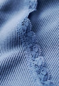 Tejido azul acanalado con un delicado encaje en el borde, que presenta patrones intrincados y una textura suave.