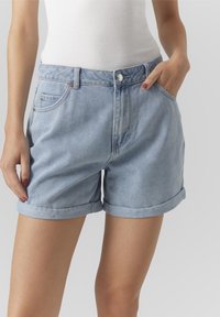 Pantalones cortos de mezclilla de color azul claro con dobladillos enrollados, que cuentan con un diseño de cinco bolsillos y un cierre frontal con botón. Hechos de un material de mezclilla suave y duradero.