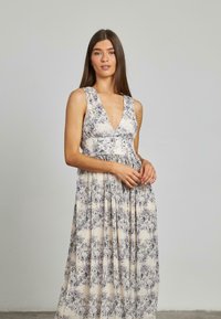 Maxi-Kleid mit tiefem Ausschnitt, eingeprägter Textur und Blumenmuster in sanften lila und creme Farben. Mit verstellbaren Trägern.