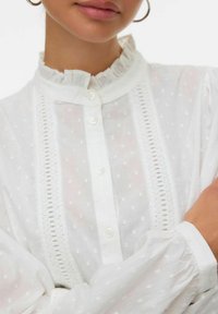 Witte blouse met een gerimpelde kraag, gemarmerde textuur, knoopsluiting aan de voorkant en kantaccenten. Volledige mouwen met gathered manchetten. Lichtgewicht stof.
