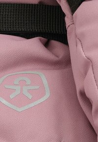 Roza teksturirana tkanina s ribjim kostmi, ki vsebuje srebrni logo in črn pleten trak. Poglej bližje material in detajle oblikovanja.