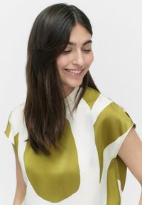 Satinbluse mit einem auffälligen grünen und wei�ßen abstrakten Muster, ausgestattet mit kurzen Ärmeln und einem lockeren Schnitt. Glatte Textur und leichtes Design.