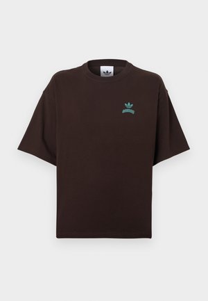 Barna pamut póló laza szabással, rövid ujjú, kerek nyakkivágással és türkizkék Adidas logóval a mellkasán. Simább tapintású anyag.