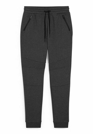 Pantalon de jogging gris foncé fuselé avec taille élastique, cordons de serrage noirs, poches latérales zippées et détails côtelés au niveau des genoux et des chevilles.