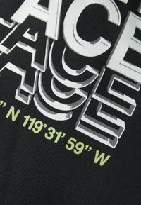 Tela negra con texto en blanco y gris en capas y de gran tamaño, con coordenadas geográficas en verde claro, creando un contraste visual texturizado.