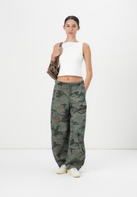 Valge ilma varrukateta crop top, roheline varjunditega kamuflaažimustriga laiad püksero, ja valged tossud. Pruun käekott tekstuursete detailidega.