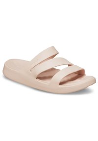 Vaaleanpunaiset Crocs-liukurit, joissa on kaksi leveää nauhaa ja avoin kärki. Valmistettu pehmeästä muovimateriaalista, jossa on teksturoitu pohja.