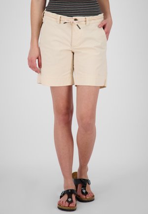 Beige Shorts mit einem Kordelzugbund, zwei Seitentaschen und einem umgeschlagenen Saum. Getragen mit schwarzen Sandalen, die eine silberne Schnalle haben.