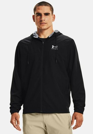 Giacca leggera nera con zip frontale, cappuccio regolabile e interno foderato grigio. Presenta il logo Under Armour sul petto e maniche lunghe.