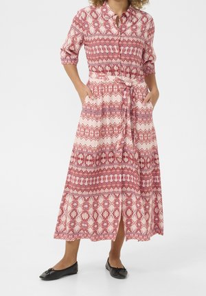 Langes, rosa und rot gemustertes Kleid mit Kragen, Knopfleiste, tailliertem Schnitt und Taschen. Es zeigt ein geometrisches Design und einen fließenden Rock.