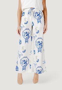 Pantaloni a gamba larga in tessuto bianco decorati con motivi floreali e geometrici blu. Presentano una vita elastica con lacci di regolazione.