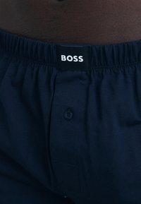 Sötét tengerészkék boxer alsó, puha anyagból készült, elasztikus derékkal, melyen a "BOSS" feliratú címke és gombos zárás található.